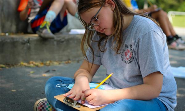 student writes on clipboard